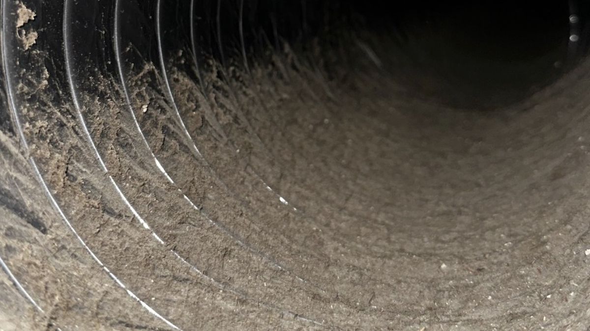 Flexible air duct coated with debris before professional cleaning