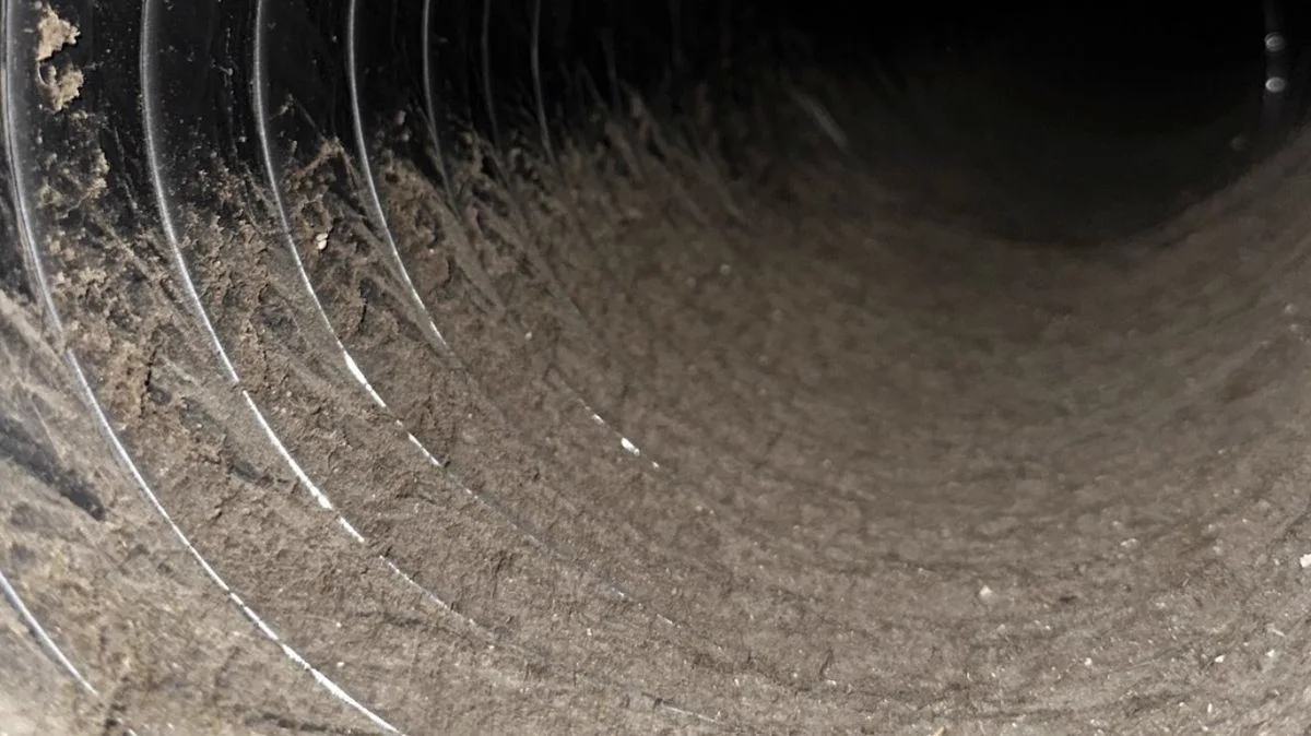 Flexible air duct coated with debris before professional cleaning