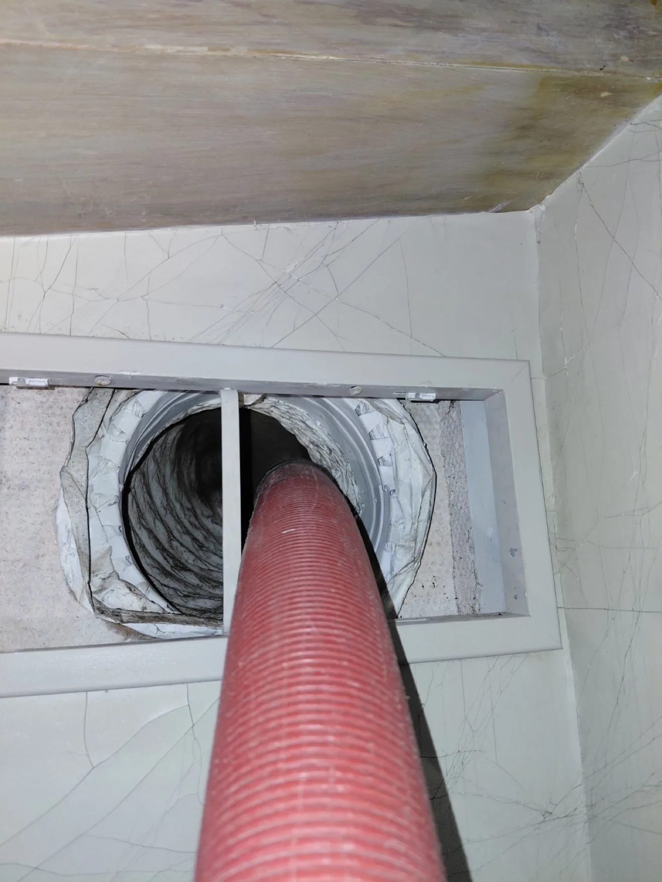 High-powered vacuum hose inserted into the return air duct during cleaning