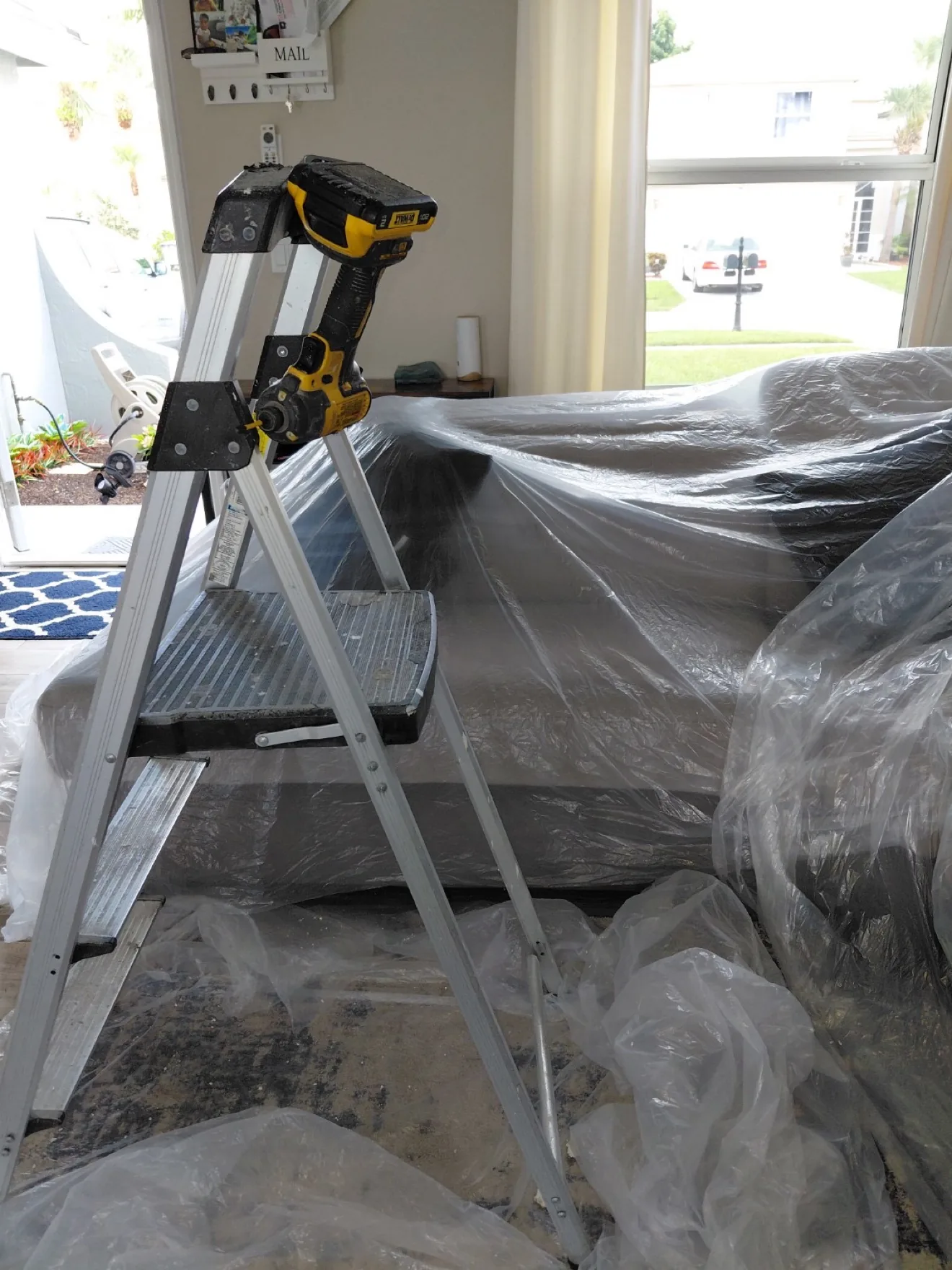 Ladder setup with furniture protected while technicians clean overhead vents